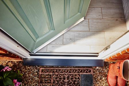 Close up of the threshold of a Sage Green composite front door from Anglian Home Improvements