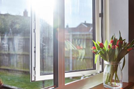 Close up of White aluminium casement window first floor opening onto garden from the Anglian aluminium windows range