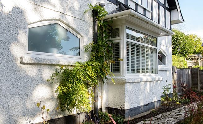 White UPVC shaped window and bay casement window with new guttering from Anglian Home Improvements