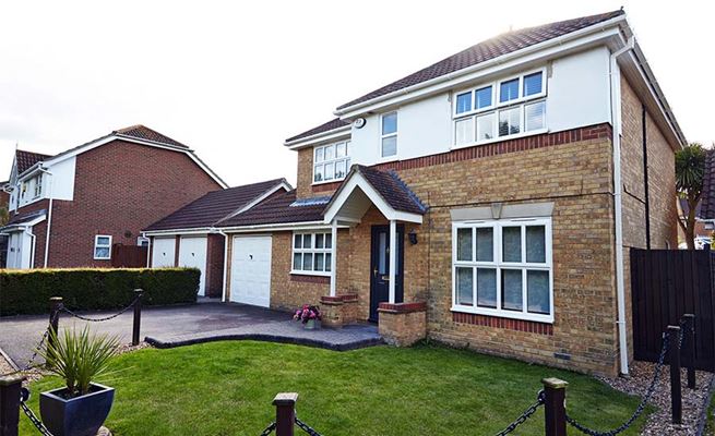 White UPVC casement windows with double glazing and UPVC guttering and new composite front door from Anglian Home Improvements