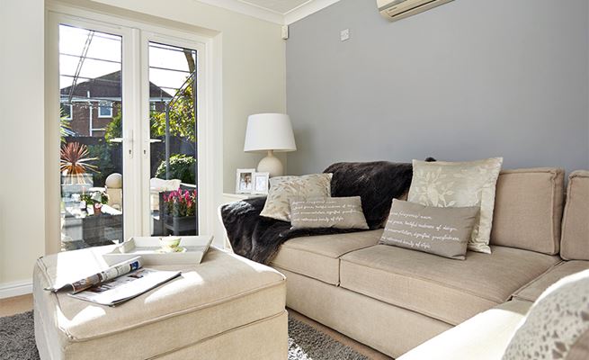 Pair of white uPVC French doors looking out onto garden patio from living room with neutral colour scheme