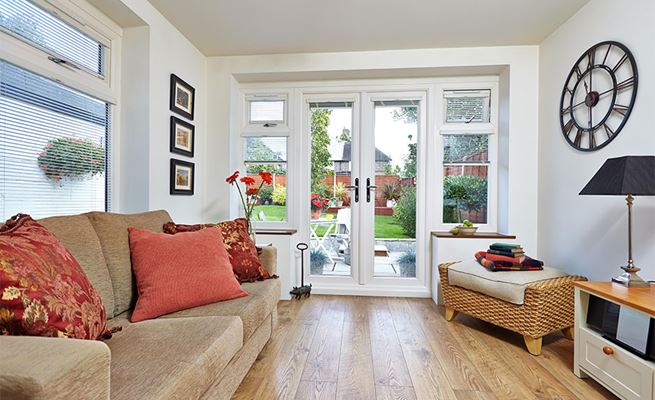 Pair of White uPVC French doors on modern living room extension with side casement windows and blinds