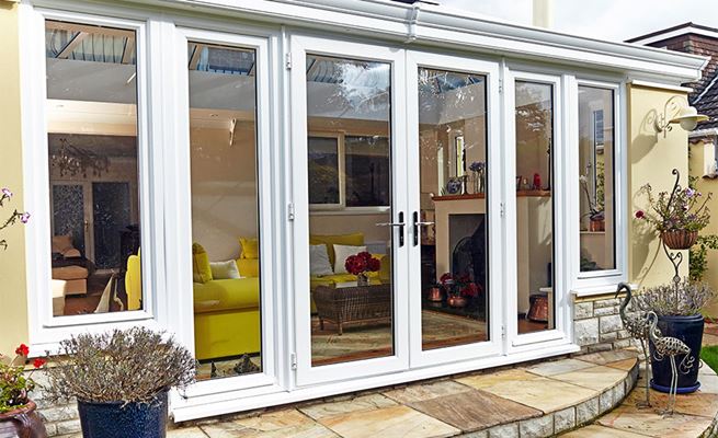 White uPVC French doors with large side uPVC double glazed casement windows on cream rendered house