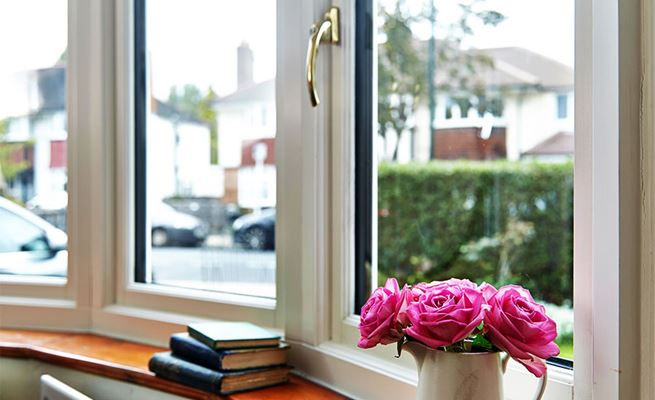 Close up of White wooden bay window with double glazing and gold window handles from the Anglian bay window range