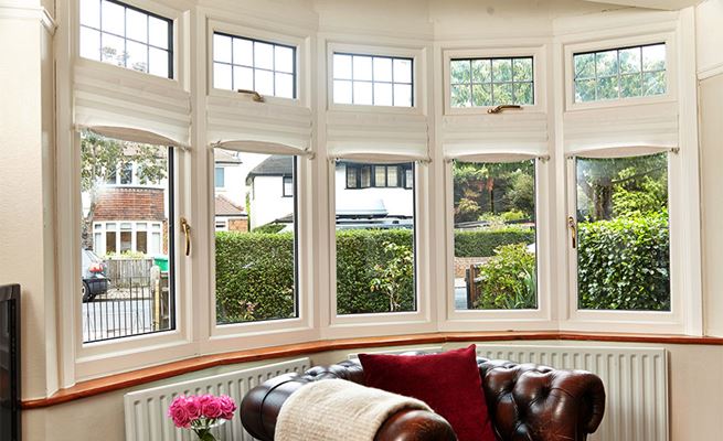 Large wooden bay casement window finished in White with leaded bars and gold window handles from Anglian Home Improvements