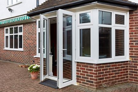 Triple glazed UPVC windows and French doors finished in white on a shaped porch from Anglian Home Improvements