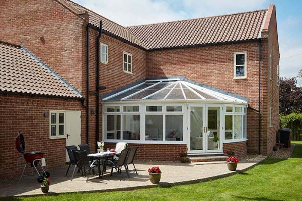 White woodgrain Victorian uPVC conservatory with French doors finished with gold handles on modern family home