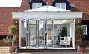 White aluminium bi-fold doors made up of five panels on an orangery from Anglian Home Improvements