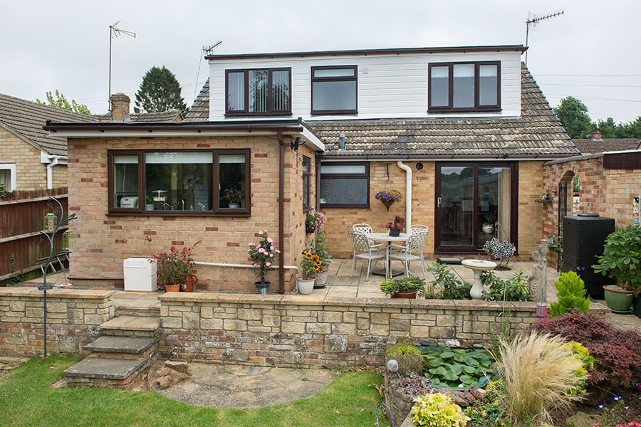 White uPVC Feather edge claddign with dark woodgrain windows whole house