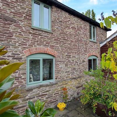Shaped uPVC casement windows in sage green