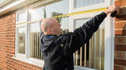 Anglian surveyor measures up exterior of home for new double glazed windows